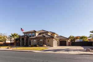 Mediterranean / spanish house featuring a garage, stone siding, a tiled roof, a gate, and stucco siding