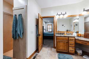 Bathroom with stone tile flooring, visible vents, ensuite bathroom, vanity, and baseboards