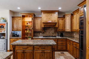 Kitchen with stone finish floor, appliances with stainless steel finishes, backsplash, and recessed lighting