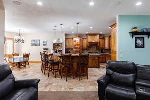 Kitchen with stone tile flooring, open floor plan, a breakfast bar area, and recessed lighting