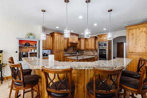 Kitchen with arched walkways, recessed lighting, stainless steel appliances, backsplash, and a large island with sink