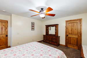 Bedroom with a textured ceiling, carpet flooring, a ceiling fan, and baseboards