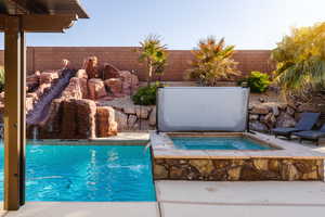 View of pool featuring a fenced in pool, a fenced backyard, and an in ground hot tub