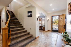 Foyer featuring arched walkways, stone tile flooring, baseboards, and recessed lighting