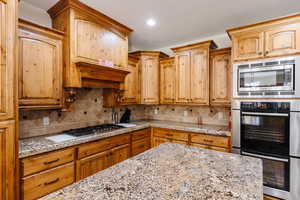 Kitchen featuring a textured ceiling, stainless steel appliances, tasteful backsplash, and light stone countertops