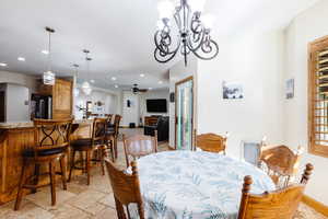 Dining room featuring arched walkways, ceiling fan with notable chandelier, recessed lighting, and stone tile floors