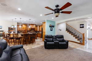 Living area featuring stone tile floors, stairs, arched walkways, and recessed lighting