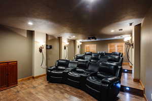 Cinema room with a textured ceiling, recessed lighting, wood finished floors, visible vents, and baseboards