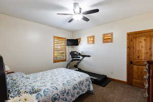 Carpeted bedroom with a ceiling fan, a textured ceiling, and baseboards