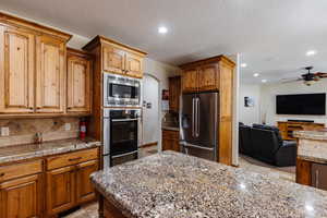 Kitchen with arched walkways, recessed lighting, open floor plan, appliances with stainless steel finishes, and decorative backsplash