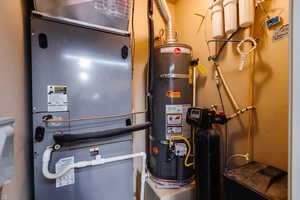 Utility room featuring heating unit and strapped water heater