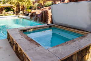 View of pool featuring a fenced in pool, a patio, and an in ground hot tub