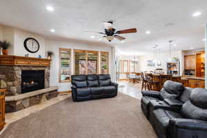 Living area with recessed lighting, a healthy amount of sunlight, light colored carpet, and a stone fireplace