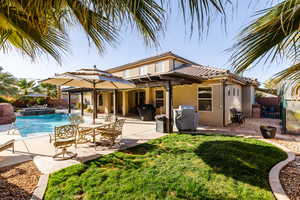 Back of property with a tiled roof, a lawn, fence, and stucco siding