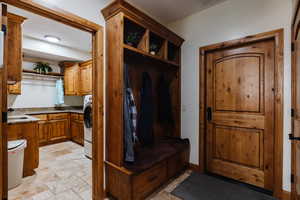 Mudroom with baseboards, washer / clothes dryer, a sink, and stone tile floors