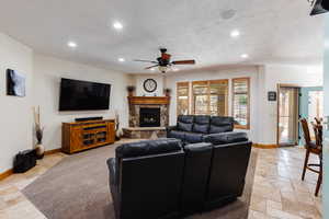 Living room with stone tile floors, baseboards, a textured ceiling, and recessed lighting