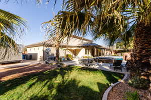 Rear view of property featuring a tile roof, a patio, stucco siding, a lawn, and an outdoor pool