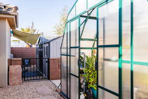 View of gate with a greenhouse, an outdoor structure, and fence