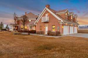 View of front facade with a balcony, a front yard, concrete driveway, and brick siding