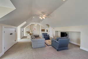 Living area with visible vents, baseboards, ceiling fan, carpet, and vaulted ceiling