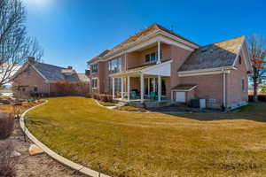 Back of property with brick siding, a lawn, and central AC unit