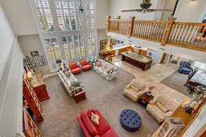 Living room featuring a ceiling fan and a towering ceiling