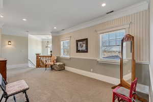 Sitting room with carpet, crown molding, visible vents, an upstairs landing, and baseboards