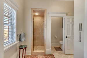 Bathroom with toilet, a stall shower, and baseboards