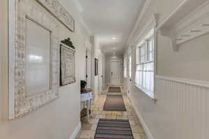 Hall featuring recessed lighting, baseboards, ornamental molding, wainscoting, and stone tile flooring