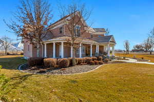 Exterior space with brick siding, a lawn, a porch, and fence