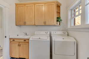 Laundry room featuring washer and clothes dryer, a sink, and cabinet space