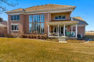 Rear view of house with a yard, french doors, brick siding, and central AC unit