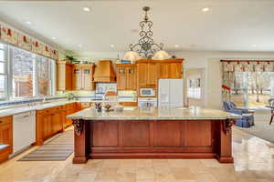 Kitchen featuring premium range hood, white appliances, a sink, a large island, and glass insert cabinets