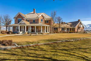 View of front of house with covered porch, brick siding, a chimney, and a front lawn