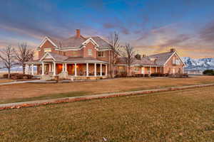 View of front of house with a front lawn, a chimney, a porch, and brick siding