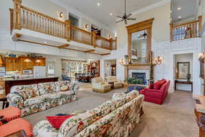 Living room with light carpet, a tiled fireplace, ornamental molding, a high ceiling, and a decorative wall