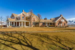 View of front of property with a porch, a chimney, and a front lawn