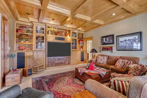 Living area with light carpet, built in features, coffered ceiling, beamed ceiling, and crown molding