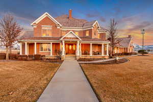 View of front of home featuring a porch, a front yard, brick siding, and a chimney