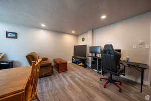 Office area featuring a textured ceiling, baseboards, wood finished floors, and recessed lighting