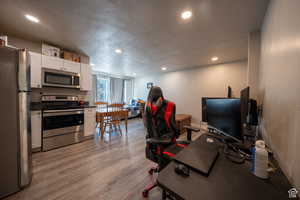 Office space featuring light wood-type flooring, a textured ceiling, and recessed lighting