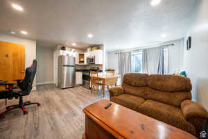 Living room with light wood-type flooring, a textured ceiling, baseboards, and recessed lighting