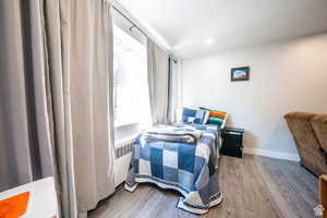 Bedroom with radiator heating unit, baseboards, wood finished floors, and recessed lighting