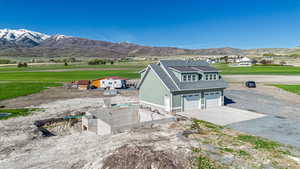 View of side of home featuring an attached garage, driveway, roof with shingles, and a mountain view