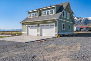 Exterior space with an attached garage, a shingled roof, driveway, and a mountain view