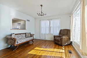 ACTUAL Living Room featuring hardwood / wood-style flooring, baseboards, visible vents, and an inviting chandelier