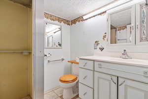 3/4 Bathroom featuring a textured ceiling, vanity, toilet, and tile patterned floors