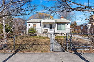 Bungalow-style house featuring a fenced front yard, a gate, and a chimney