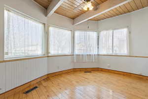 Unfurnished sunroom featuring a ceiling fan, wood ceiling, visible vents, and vaulted ceiling with beams