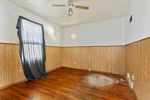 Spare room with dark wood-type flooring, wainscoting, and wood walls